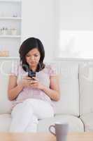 Woman sitting on a sofa while holding a phone