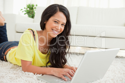 Portrait of a beaming Latin woman using a laptop