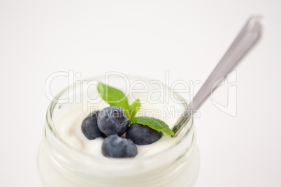 Close up of a pot of yoghurt with blueberries and fresh mint