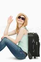 Woman sainsing her hand while sitting near a suitcase