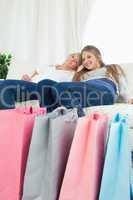 Smiling girls sitting on the couch with their bags of shopping
