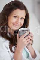 Woman holding a mug of coffee while looking at camera