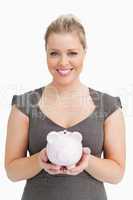 Woman showing a pink piggy bank