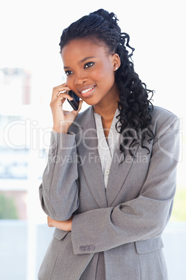 Young smiling executive woman crossing her arms while talking on