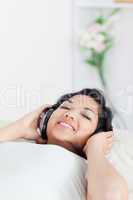 Woman smiling and lying on a sofa with headphones on