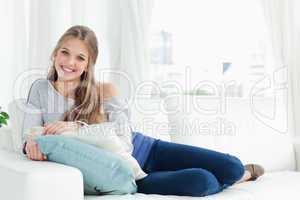 A smiling girl lying on the couch facing the camera