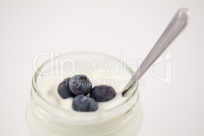 Close up of a pot of yoghurt with four blueberries