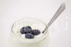 Close up of a pot of yoghurt with four blueberries