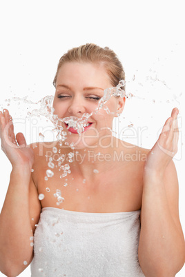 Happy blonde woman splashing her face