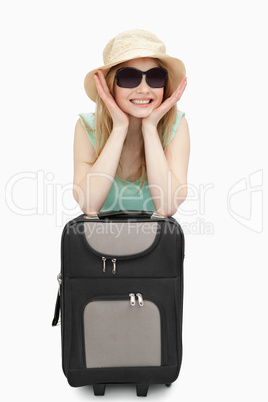 Cheerful woman leaning on a suitcase while sitting