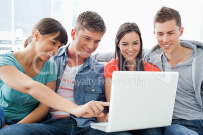 A smiling group of friends looking at the laptop with one girl p
