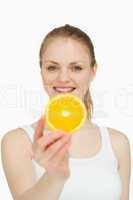 Smiling woman presenting a slice of orange