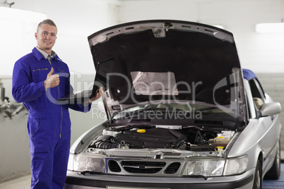 Mechanic holding a computer with thumb up