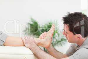 Physiotherapist sitting while massaging a foot
