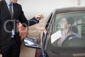 Smiling woman in a car taking keys
