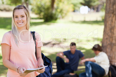 Portrait of a female student smiling while holding a textbook