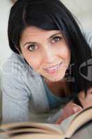 Woman holding a book while resting on a white sofa