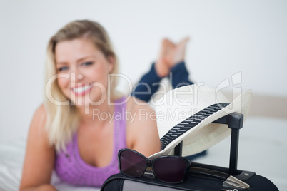 Young woman smiling behind a suitcase