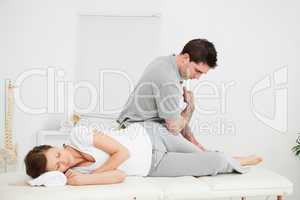 Chiropractor massaging the thigh of his patient while using his