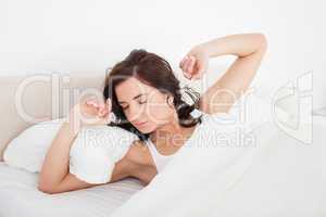 Brunette woman stretching her arms while lying