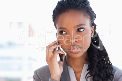 Young earnest employee talking on the phone in front of a bright