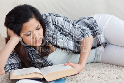 Woman reading a book as she lays on the floor