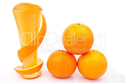 Orange peel wrapped around a glass near a pile of oranges