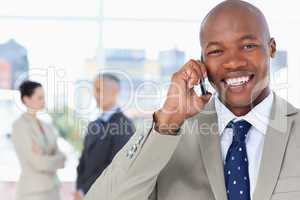 Young manager laughing while using his cell phone