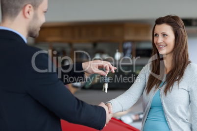Man giving car keys while shaking hand of a woman