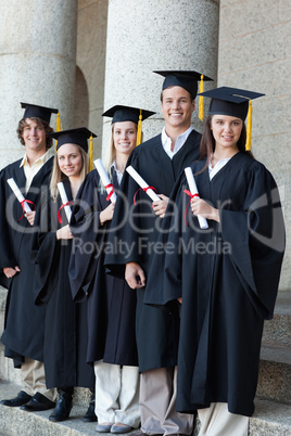 Happy graduates posing in single line