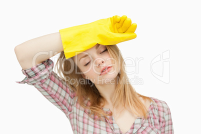 Woman wearing cleaning gloves while wiping her brow