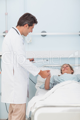 Doctor talking to his patient while holding her hand Doctor talking to his patient while holding her hand