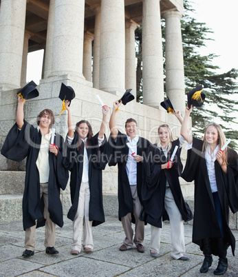 Five happy grad students raising their hats