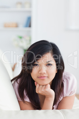 Woman holding her head with her fist while resting on a couch