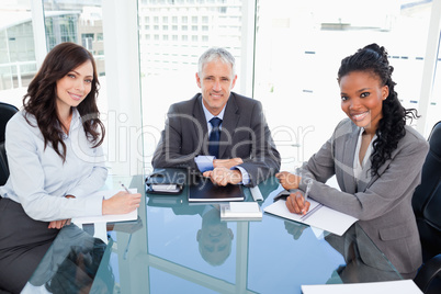 Smiling director sitting at the desk in front of the window betw