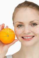 Fair-haired woman presenting an orange