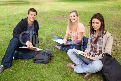 Three smiling students studying together