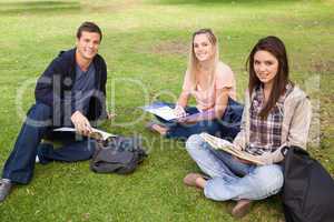 Three smiling students studying together