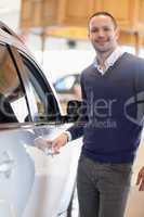 Man holding a car handle while smiling