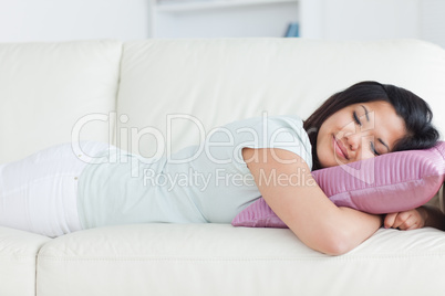 Woman sleeping on a white sofa and holding a pillow