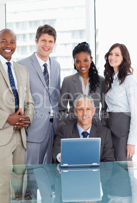 Mature businessman sitting at the desk behind a laptop and surro