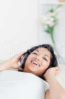 Smiling woman lying on a sofa with headphones on