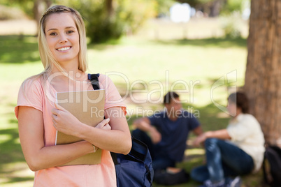 Portrait of a pretty girl smiling while holding a textbook