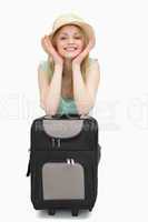 Smiling woman leaning on a suitcase while sitting