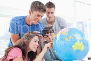 Students pointing to places in the world on a globe