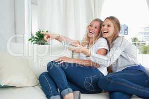 Girls laughing on the couch as they watch tv
