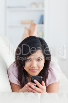 Woman lays on a sofa while texting on a phone