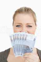 Woman hiding a middle of her face with euro banknotes