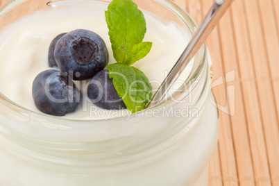 Close up of four blueberries in a pot of yoghurt