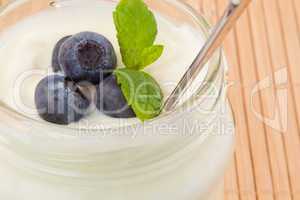 Close up of four blueberries in a pot of yoghurt